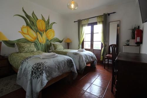 a bedroom with two beds and a flower mural on the wall at Quarto Tulipa in Vila Nova de Milfontes