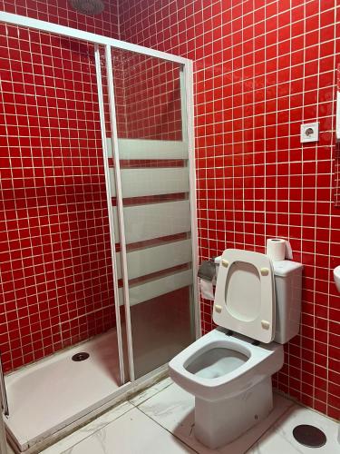 a red tiled bathroom with a toilet and a shower at Hostal Gracias in Madrid