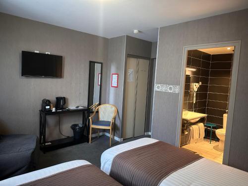 a hotel room with two beds and a television at Hotel Berthelot in Tours
