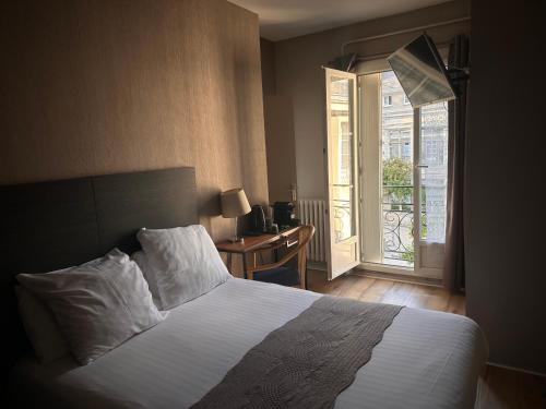 a bedroom with a bed and a desk with a window at Hotel Berthelot in Tours