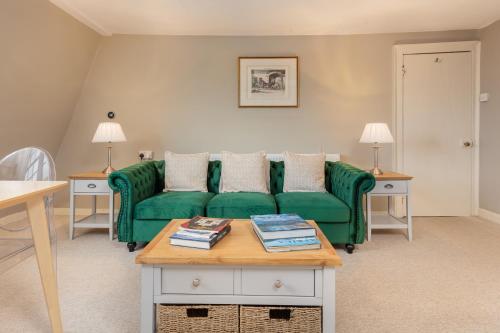 Una sala de estar con un sofá verde y una mesa. en Lovely Georgian Loft in The Very Centre of Bath, en Bath