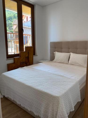 a bedroom with a large white bed with a window at Casa do Cruzeiro in Santo Adrião