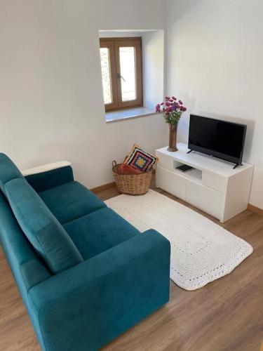 a living room with a blue couch and a tv at Casa do Cruzeiro in Santo Adrião