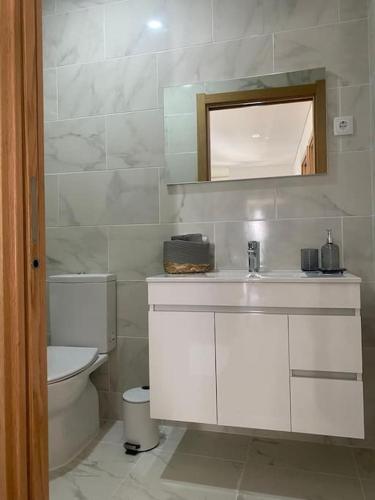 a bathroom with a toilet and a sink and a mirror at Casa do Cruzeiro in Santo Adrião