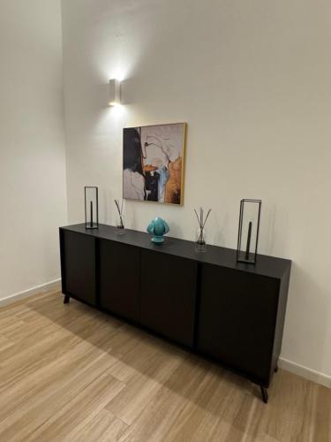 a black dresser in a room with a painting on the wall at Duomo Rooms - Manfredi Homes&Villas in Manfredonia