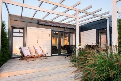 a deck with chairs and a pergola at Resto domki letniskowe in Sarbinowo
