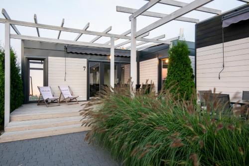 a patio with chairs and a pergola on a house at Resto domki letniskowe in Sarbinowo