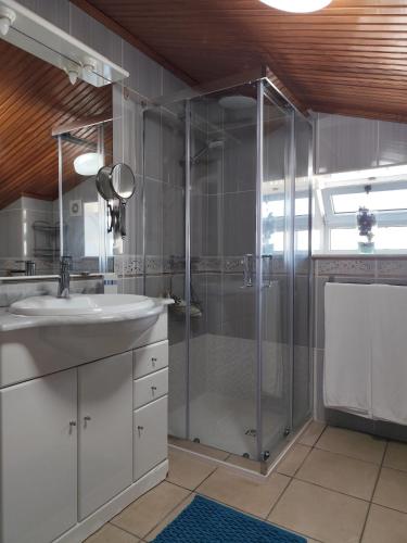 a bathroom with a glass shower and a sink at Cantinho a Sul - Costa Nova in Gafanha da Encarnação