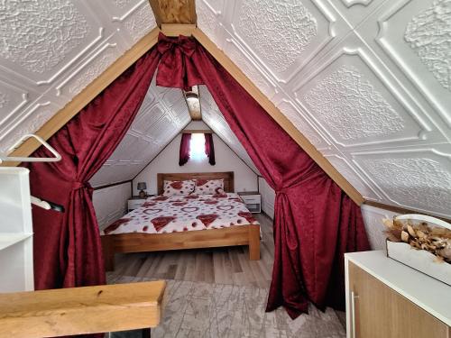 ein Schlafzimmer mit einem großen Bett mit roten Vorhängen in der Unterkunft Sunce in Bajina Bašta