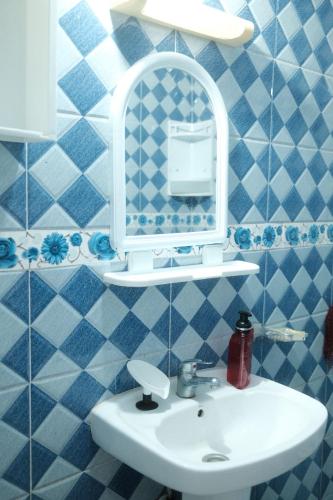 a blue tiled bathroom with a sink and a mirror at Black Pearl surf yoga and skate house in Tamraght Ouzdar