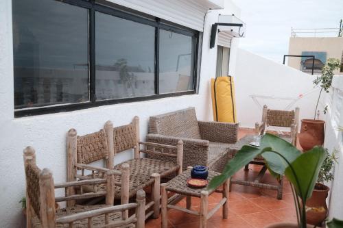 a patio with chairs and a table and a window at Black Pearl surf yoga and skate house in Tamraght Ouzdar