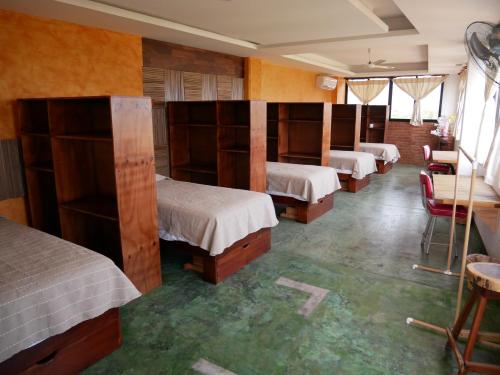 a room with four beds and a row of shelves at Madre Tierra Hostal in Puerto Escondido