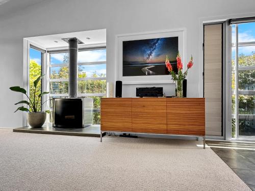 a living room with a tv and a dresser with flowers on it at Westmere Wonder l Gorgeous 3 Bed Home inc View in Auckland