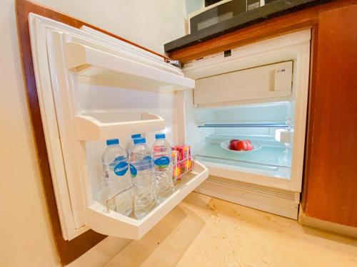 an open refrigerator with bottles of water in it at Nayah Stays, Ancient Sands Luxurious Pool Terrace Apartment in Hurghada