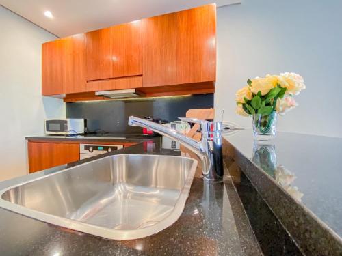 a kitchen counter with a sink and a vase of flowers at Nayah Stays, Ancient Sands Luxurious Pool Terrace Apartment in Hurghada