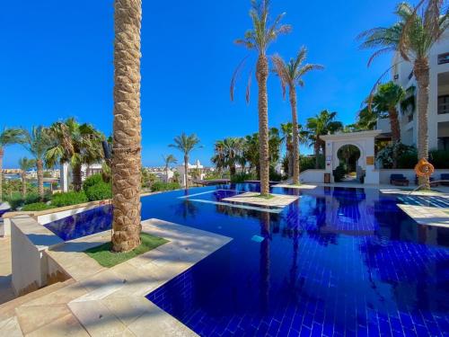 a swimming pool with palm trees in a resort at Nayah Stays, Ancient Sands Luxurious Pool Terrace Apartment in Hurghada
