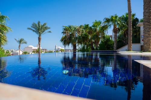 a swimming pool with palm trees in the background at Nayah Stays, Ancient Sands Luxurious Pool Terrace Apartment in Hurghada