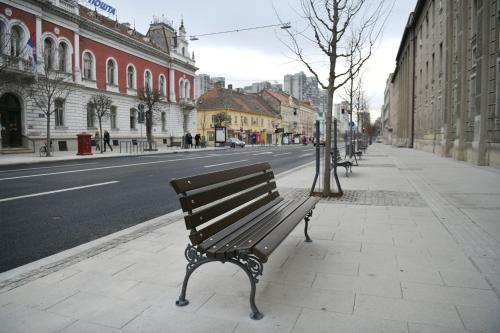 a bench on a sidewalk on a city street at White Bear 1663 Zemun Oldest House Apartment in Zemun