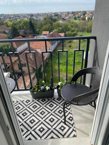 a balcony with two chairs and a table with flowers at Green Lux Apartment in Inđija