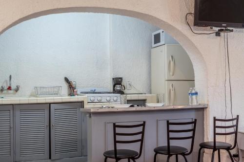 a kitchen with a counter with three bar stools at Suite para 4 con Terraza Privada, en el Corazón de Chapalita 11 in Guadalajara
