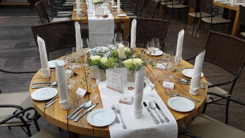 a wooden table with white plates and flowers on it at Hotel-Restaurant Pfälzer Hof in Edenkoben