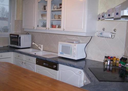 a kitchen with white cabinets and a sink and a microwave at Chambre bleue lit individuel in Combs-la-Ville
