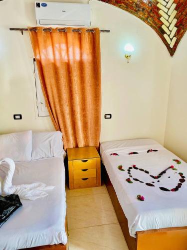a room with two beds and an orange curtain at Dangy Kato in Aswan