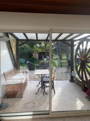 un patio ouvert avec une table et une roue dans l'établissement Maison champêtre avec vue sur un étang, à La Bussière