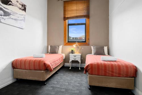 two beds in a small room with a window at Burnie City Apartments in Burnie