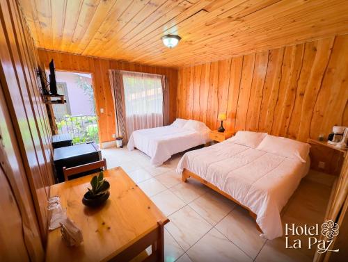 a bedroom with two beds and a table and a table sidx sidx sidx at Hotel La Paz in Poasito