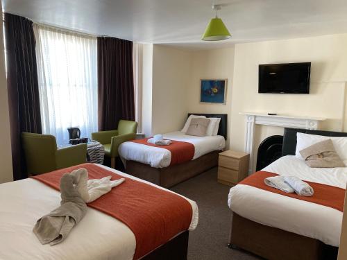 a hotel room with two beds and a tv at Old Palace Guest House in Brighton & Hove