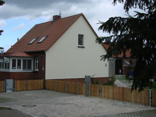 Strodehne的住宿－Ferienwohnungen Spiesmacher，白色的房子,有棕色的屋顶和栅栏
