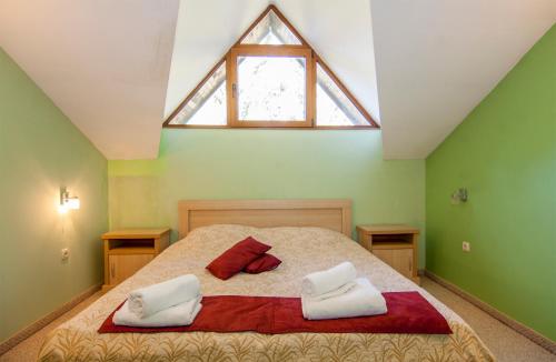 Un dormitorio con una cama con dos almohadas y una ventana. en Апартаменти Малина, en Pamporovo