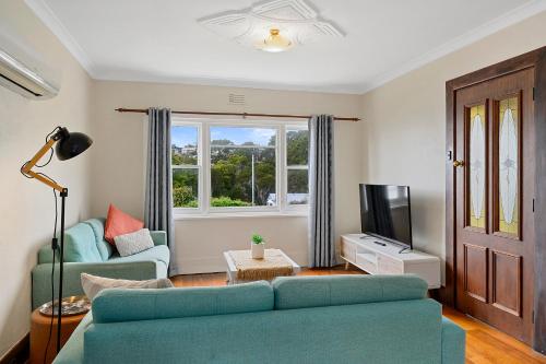a living room with a couch and a tv at Burnie City Apartments in Burnie