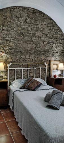 a bed in a room with a stone wall at Cueva En El Geoparque de Granada in Bejarín