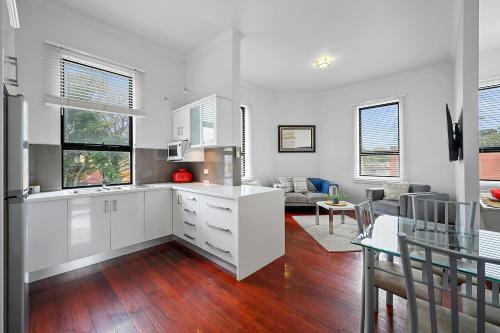 a kitchen with white cabinets and a living room at Burnie City Apartments in Burnie
