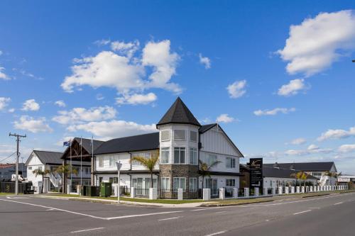 a white house with a black roof on a street at Newina Rotorua in Rotorua