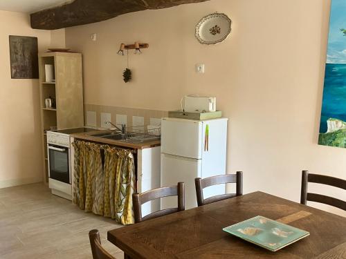 a kitchen with a table and a white refrigerator at La petite pommeraie in Sommervieu