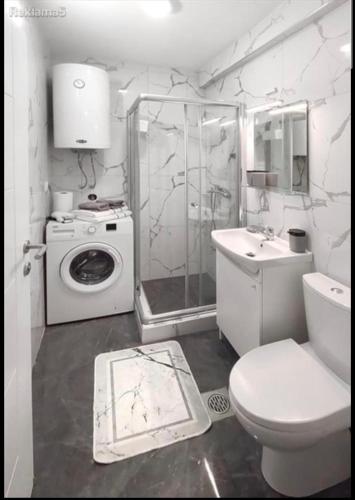 a bathroom with a toilet a sink and a washing machine at Luxury Skopje Apartments in Skopje
