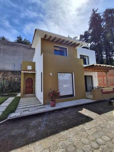 a small white and yellow house with a driveway at Las casas de las flores in Ibarra