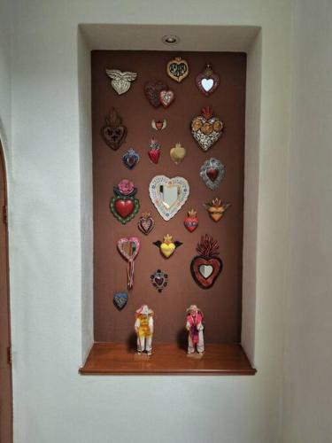 a wall with hearts and two figurines on a shelf at Las casas de las flores in Ibarra