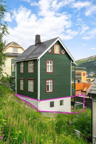 una grande casa verde seduta in cima a una collina di Leilighet i sentrum av Tromsø a Guleng