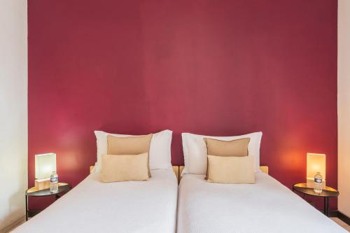 two beds in a room with a red wall at Amanthos Living Nyon in Duillier