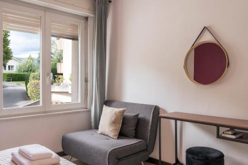 a room with a chair and a mirror and a window at Amanthos Living Nyon in Duillier