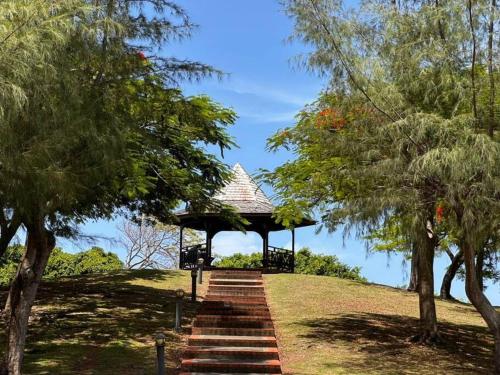 a stairway leading to a gazebo on a hill with trees at Bambou Suite vue mer à 50 m de la plage et de la piscine in Sainte-Luce