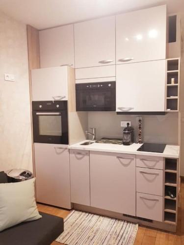 une cuisine avec des armoires blanches et un appareil noir dans l'établissement Studio Paris Montmorency, à Paris