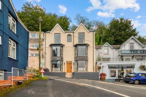 a house on a street with a blue building at Panoramic Sea View Apartment in The Mumbles