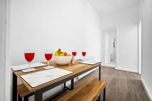 a table with wine glasses and a bowl of fruit at 1 Bed Apartment Birmingham Resorts World NEC BHX in Birmingham