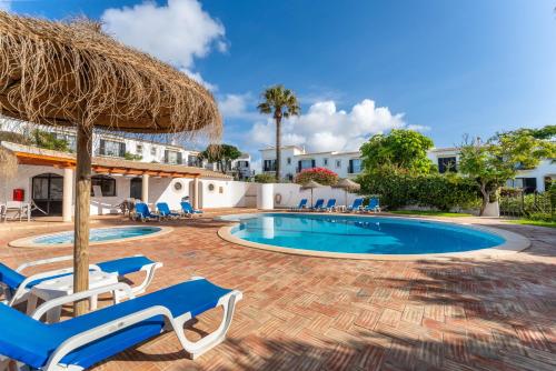 a swimming pool with chairs and a straw umbrella at Casa Matea in Figueira