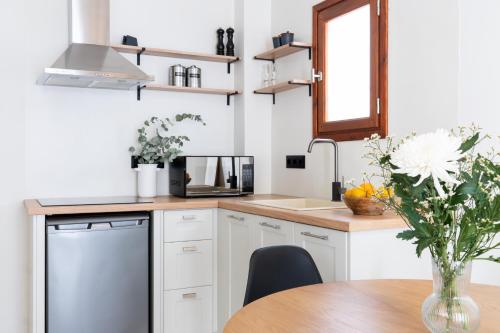a kitchen with white cabinets and a table with a vase of flowers at Olea White in Skiathos Town